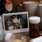 Warm and inviting indoor scene with a family photo, nested dolls, mugs, and medication bottles on a table.