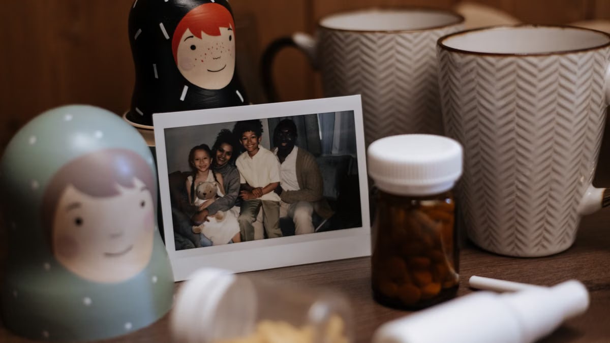 Warm and inviting indoor scene with a family photo, nested dolls, mugs, and medication bottles on a table.